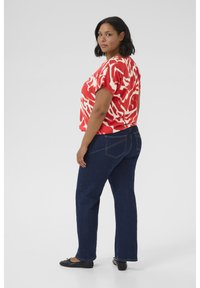 Un haut à manches courtes à motifs rouges et blancs associé à un jean droit bleu foncé. La tenue présente une coupe décontractée et un design minimaliste.