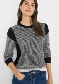 Maglione a maglia strutturata in nero e grigio, con dettagli a coste, scollo rotondo e polsini risvoltati. Sovrapposto con un orlo bianco.