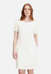 Weißes Kurzarmkleid mit Lochmuster, rundem Halsausschnitt und seitlichen Taschen. Glatte Textur, knielanges Design.