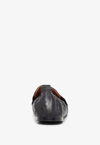 Zapato negro de piel sin cordones con una textura suave y punta redondeada. Presenta un diseño minimalista y un tacón bajo y robusto.