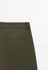 Pantalon sur mesure vert olive vu de dos, montrant la taille, les passants de ceinture et une seule poche passepoilée sur le côté droit.