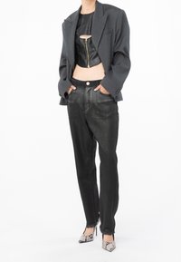 Top de cuero negro cropped con cremallera frontal, combinado con pantalones negros de corte holgado y una chaqueta gris estructurada. Tacones de piel de serpiente completan el look.