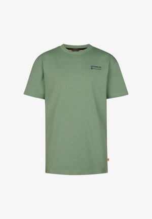 Zielona bawełniana koszulka z krótkim rękawem i okrągłym dekoltem, w zestawieniu z granatowymi dresami i białymi tenisówkami. Prosty design bez wzorów.