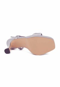 Scarpa con tacco alto argento dal superficie liscia, con cinturini texture e soletta leggermente imbottita. Presenta una punta affusolata e un tacco elegante.