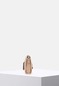 Borsa a tracolla in pelle beige con finitura testurizzata, dotata di una zip laterale, un manico corto e un piccolo tag decorativo.