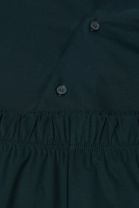 Dark green fabric featuring a button closure and gathered detailing at the waist, with smooth texture and subtle stitch lines.