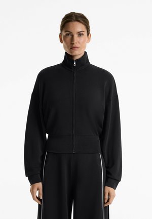 Black cropped zip-up sweatshirt with high collar and long sleeves, featuring a smooth texture and subtle white accents on cuffs.