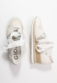 Vita sneakers i texturerat läder och mesh-material, med ett brett vitt snöre. Sula med naturlig vävd detalj och beige accenter.
