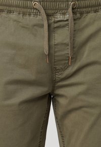 Olive green cotton pants with an elastic waistband, featuring a drawstring and subtle stitching details. Smooth surface texture.