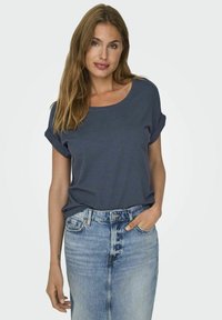 T-shirt bleu marine à manches courtes avec des poignets retroussés, fabriqué en coton doux, associé à une jupe crayon en denim bleu clair. Design simple et décontracté.