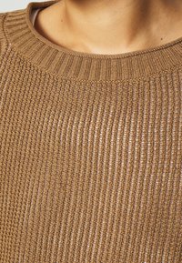 Maglione marrone lavorato a maglia con colletto a coste e tessuto testurizzato. Presenta un motivo a trama morbida e finitura soffice.