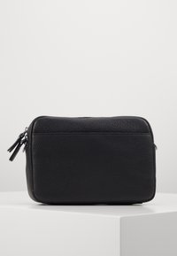 Borsa rettangolare in pelle nera con una texture a granuli, dotata di doppia cerniera e un design semplice e minimalista. Nessun accento di hardware visibile.