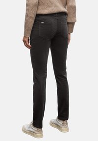 Svarta jeans med en slim fit-design, tillverkade av mjukt tyg. Har två bakfickor och en liten logotyp på midjebandet.