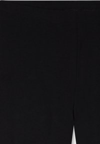 Czarne legginsy wykonane z gładkiego, elastycznego materiału. Posiadają szeroką gumkę w pasie i brak widocznych szwów, co zapewnia minimalistyczny design.