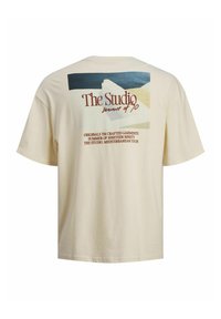 Crèmekleurig katoenen T-shirt met een grafische print op de achterkant met abstracte vormen, tekst in bruin en blauwe tinten, en een relaxte pasvorm.