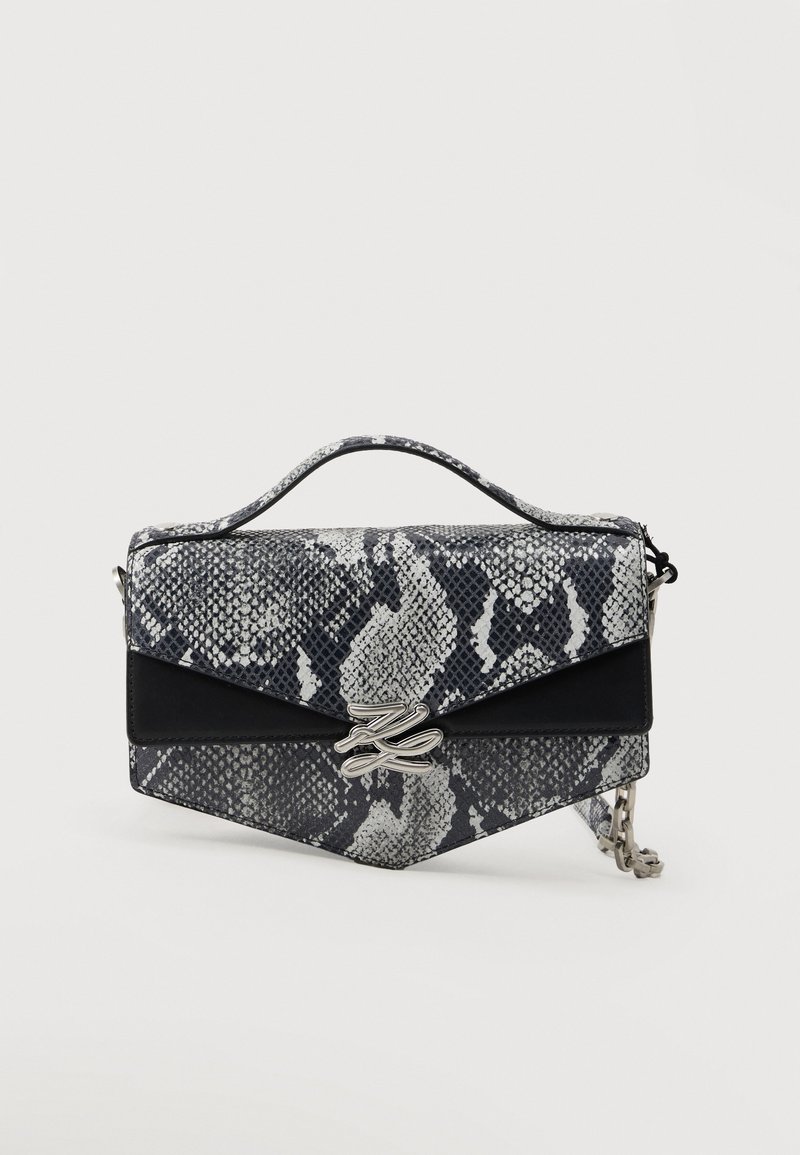 Μικρή ορθογώνια τσάντα χειρός με ασπρόμαυρο τύπωμα φιδιού, μαύρο καπάκι με διακοσμητική πινελιά, ασημένιο κούμπωμα με λογότυπο, κοντή λαβή στο πάνω μέρος και αλυσίδα ιμάντα σε λευκό φόντο.