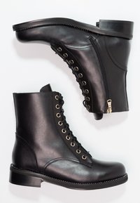 Černé kožené kotníkové boty s tkaničkami vpředu, bočním zipem, kulatou špičkou a podrobným prošíváním podél podrážky. Plochý podpatek s hladkým povrchem.