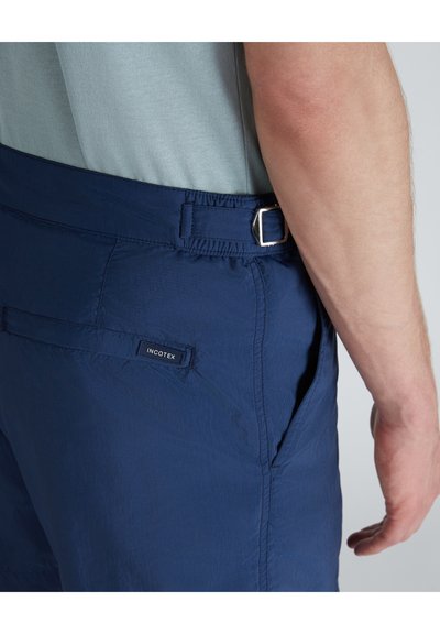Marineblaue Shorts aus leichtem Stoff mit einem elastischen Bund, verstellbaren Schnallen und einem aufgenähten Logo auf der Gesäßtasche.