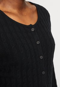 Czarny dziergany kardigan z fakturowanym wzorem warkocza, okrągłym dekoltem oraz pięcioma zapięciami na ciemne guziki.