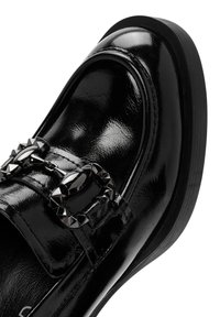 Mocassino in vernice nera con punta arrotondata, dotato di accessori decorativi in metallo nero e finitura liscia. Suola in gomma piatta.