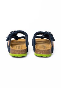 Sandales en daim bleu marine avec des brides réglables, semelle en liège et semelle extérieure en caoutchouc vert. Comprend une étiquette de marque rectangulaire.
