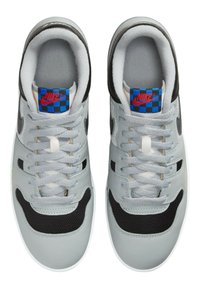 Gray leather sneakers with black mesh accents, flat laces, and a checkered blue and black tongue featuring a red Nike logo.