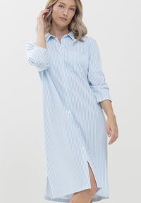Robe longue à boutons avec des rayures verticales bleu clair et blanches, dotée d'un col, d'une poche poitrine et d' fentes latérales pour faciliter les mouvements.