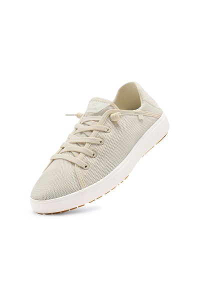 Beige mesh sneaker met witte zool, elastische veters en een merkembleem op de tong, afgebeeld vanuit een lichte hoek op een witte achtergrond.