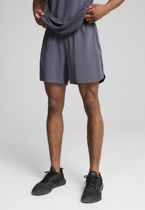 Gray athletic shorts made of lightweight fabric, featuring an elastic waistband and a relaxed fit, paired with black sneakers.