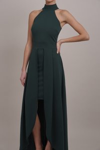 Tamnozeleni halter haljina s pripijenim korzetom i lepršavom suknjom koja ima visoki prorez. Izrađena je od mekanog, glatkog materijala s jednostavnim dizajnom.
