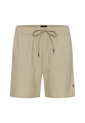 Beige swim shorts with an elastic waistband and adjustable drawstring. Textured fabric with a side logo detail. Standard fit.