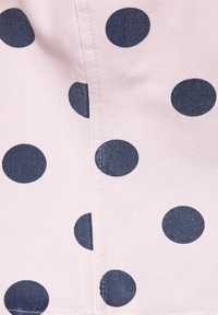 Tissu rose clair avec de grands pois bleu foncé régulièrement espacés et une couture verticale au centre.