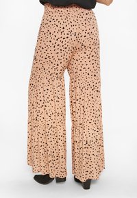 Rózsaszín, laza szabású nadrág, réteges dizájnnal, fekete pöttyös mintázattal. Rugalmas derékpánt és texturált anyag.