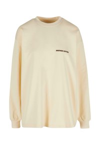 Sweatshirt en coton oversized couleur crème avec de longues manches et des poignets côtelés, arborant un petit logo marron "ANOTHER COTTON" à l'avant.