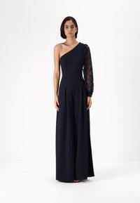 Navy blue dress with one shoulder design; the other sleeve features lace detailing. Fabric is smooth with a wide-leg cut and pleats.
