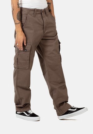 Brown cargo pants with multiple pockets, made of durable fabric. They have a loose fit and feature a zipper fly and belt loops. Black sneakers are worn.