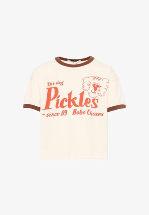 T-shirt crème à manches courtes avec col et poignets marron, portant un texte orange « Le chien Pickles depuis 09 Bobo Choses » et un visage de chien cartoon.