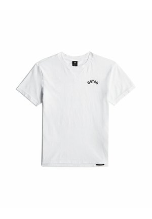 T-shirt blanc à manches courtes et col rond avec le logo G-STAR sur la partie supérieure gauche de la poitrine et une petite étiquette noire près de l’ourlet.