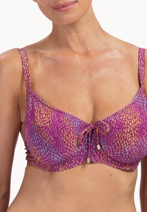 Frau trägt ein lila Bikinioberteil mit blauen und gelben Blattmustern und einer vorderen Bindung, dargestellt vom Hals bis zur Mitte des Bauches.