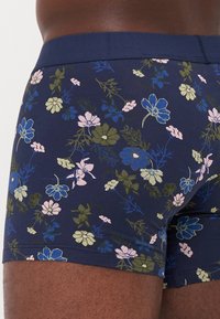 Mörkblå blommiga boxershorts med en blandning av rosa, gröna och blå blommor, tillverkade av ett mjukt och elastiskt material med en enfärgad midja.