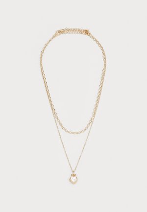 Collier en or plaqué comportant un pendentif en forme de cœur avec une surface texturée, des maillons de chaîne en or interconnectés et un fermoir réglable.