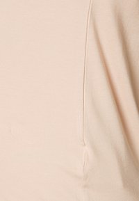 Tecido de algodão rosa claro com uma textura suave, apresentando um detalhe de costura discreto na lateral. Design simples, sem padrões ou acentos distintos.