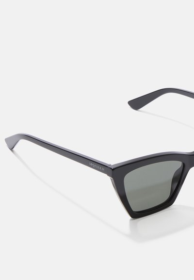 Gafas de sol de plástico negro con lentes verde oscuro. Diseño de marco angular con patillas delgadas, que presentan un logo sutil en un brazo.