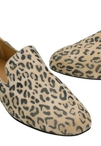 Scarpe beige senza lacci con macchie nere a forma di leopardo, punte arrotondate e texture liscia, vista dall'alto e dalla parte anteriore.
