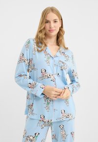 Blaues Pyjama-Set mit verspieltem Dalmatiner-Muster, aus weichem Stoff gefertigt, mit knöpfbarer Oberseite und passender Hose. Mit rosa Akzenten gesäumt.