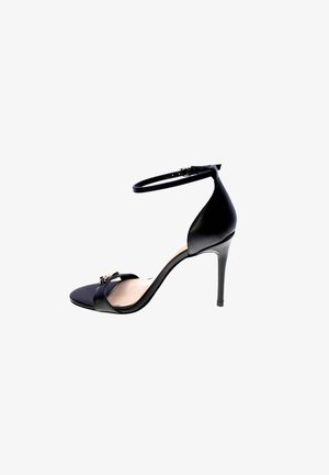 Sandalo nero con tacco alto, cinturino alla caviglia e punta aperta, con una piccola fibbia decorativa sulla fascia frontale.