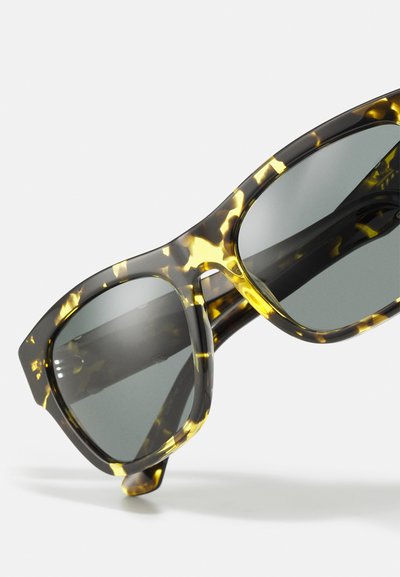 Ochelari de soare cu model țestoasă, cu un finisaj lucios, având modele gri și galbene, lentile închise la culoare și un cadru robust cu un design unghiular.