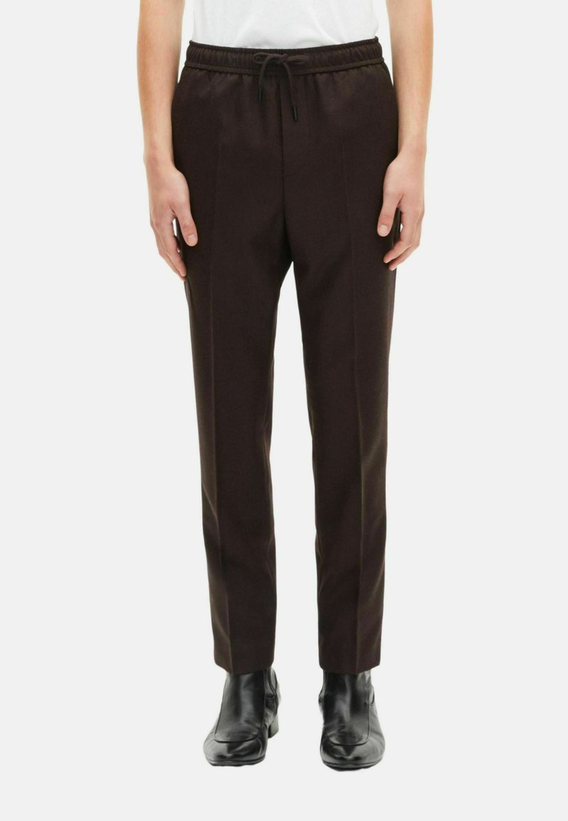 Brown, slim-fit broeken met een elastische tailleband en trekkoord, voorzien van zijplooien en een gladde textuur, gecombineerd met zwarte laarzen.