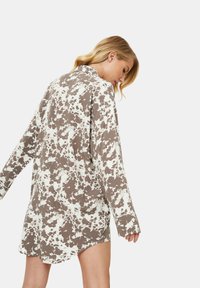 Czarna sukienka w białe kropki z długimi rękawami, kołnierzykiem i luźnym krojem, z zaokrąglonym dołem i miękką fakturą.