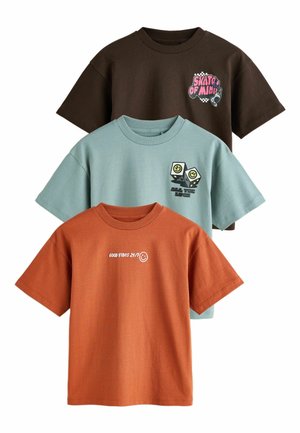 Trzy koszulki z krótkim rękawem: brązowa z różowo-czarną grafiką, jasnoniebieska z zieloną grafiką oraz pomarańczowa z białym napisem. Materiał bawełniany, dekolt okrągły.